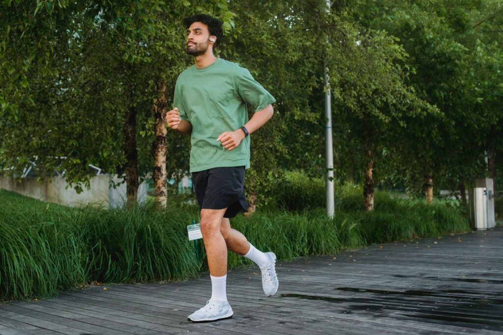 A confident young man jogging in a green park, enjoying a healthy lifestyle.